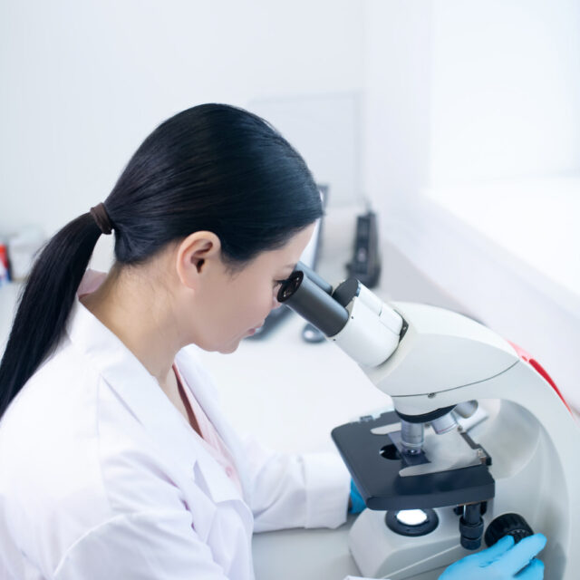 Microscopic view. Dark-haired doctor in a white robe working in the laboratory